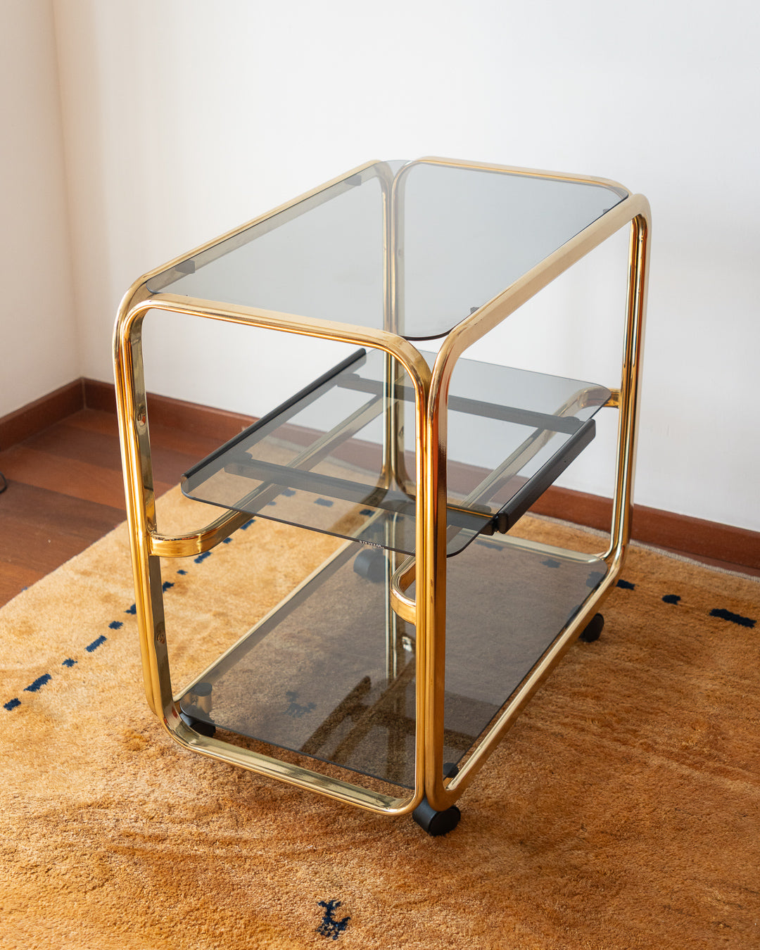 Vintage 1970s gold and smoked glass 3-tier side table, middle sliding shelf, wheels, polished and restored, very good condition | Vecino Shop