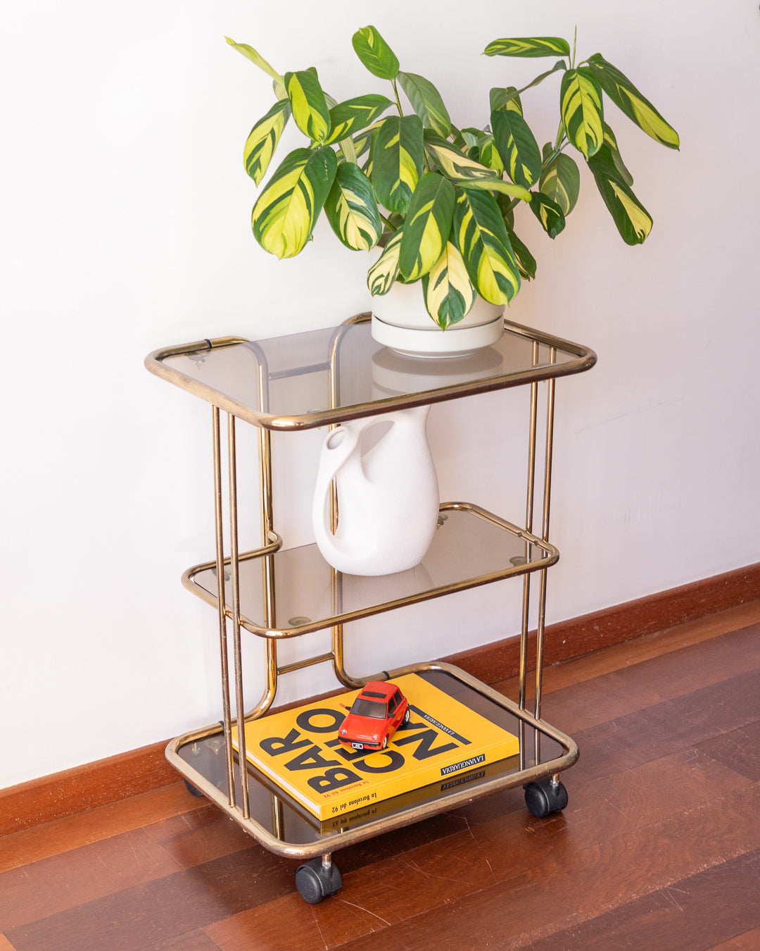 Vintage 1970s gold and smoked glass 3-tier rolling table with worn gold finish