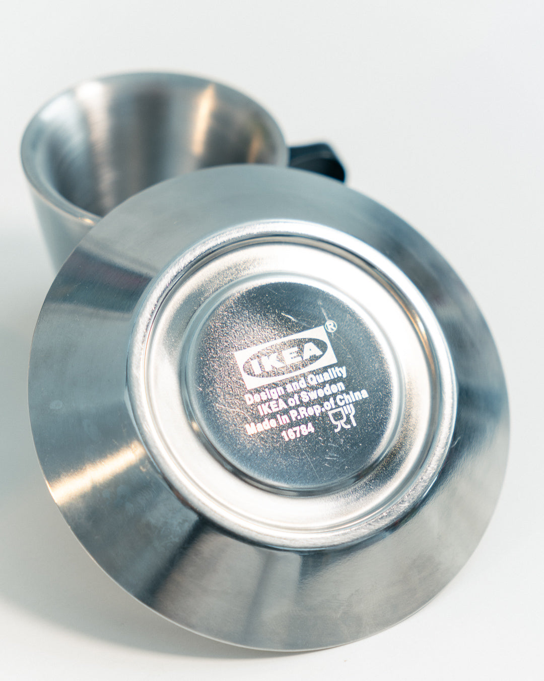 Vintage IKEA double-walled stainless steel espresso cup and saucer set from the 1990s with black plastic handles. Scandinavian minimalist design. Vecino Shop