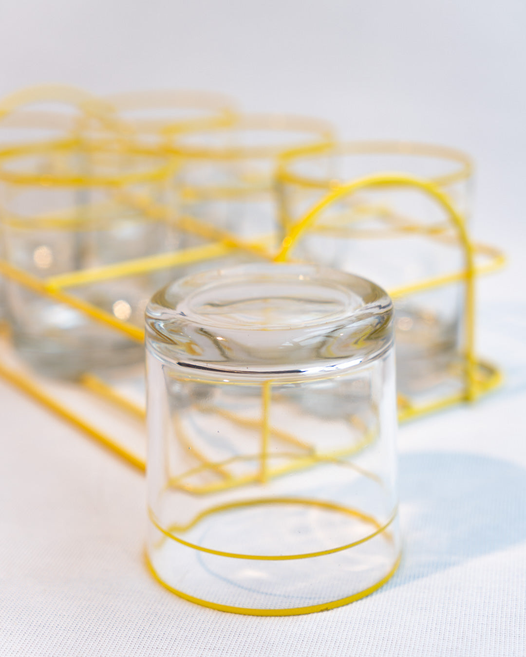 Set of six vintage clear glasses with yellow stripes in a yellow metal serving rack, retro drinkware display - Vecino Shop