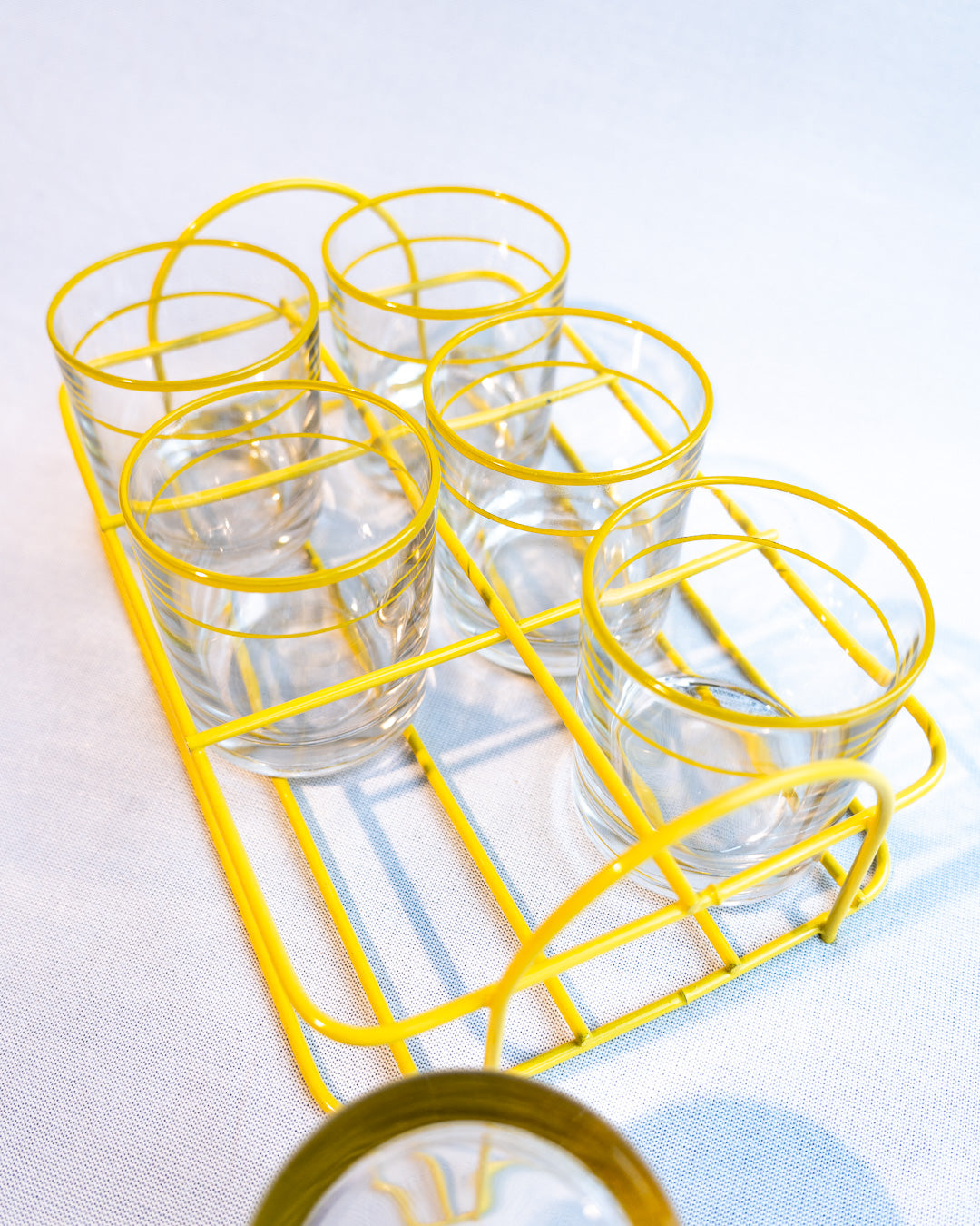 Set of six vintage clear glasses with yellow stripes in a yellow metal serving rack, retro drinkware display - Vecino Shop