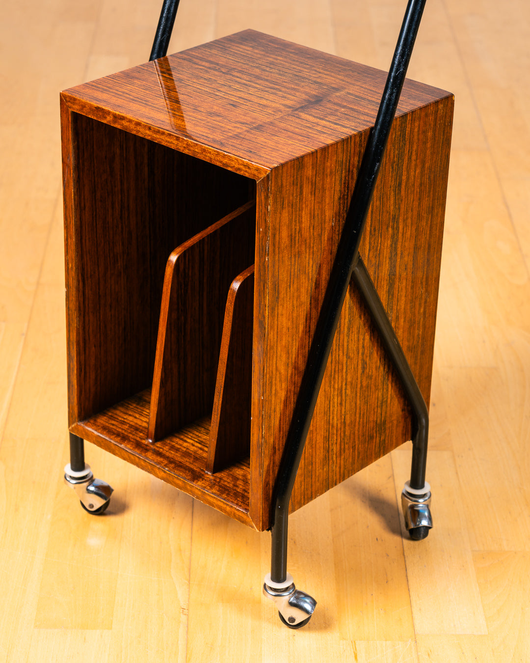Vintage 1950s mid-century modern rolling side table, wood veneer, tubular black metal frame, chrome wheels, built-in bookcase. Vecino Shop