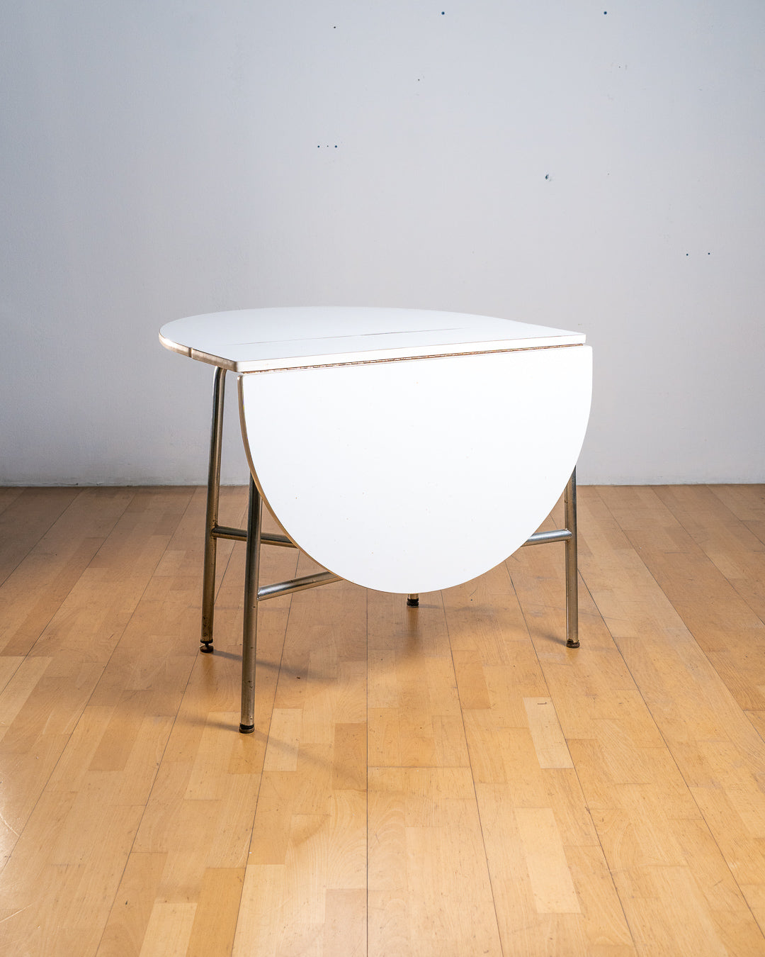 Vintage 1970s round folding dining table with chrome tubular legs and white Formica top. Space-saving design with three positions. Vecino Shop