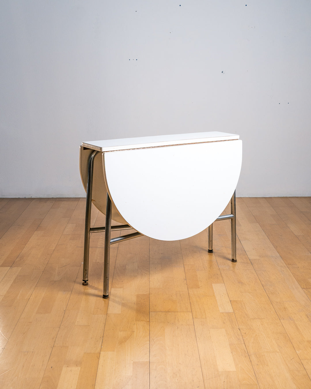 Vintage 1970s round folding dining table with chrome tubular legs and white Formica top. Space-saving design with three positions. Vecino Shop