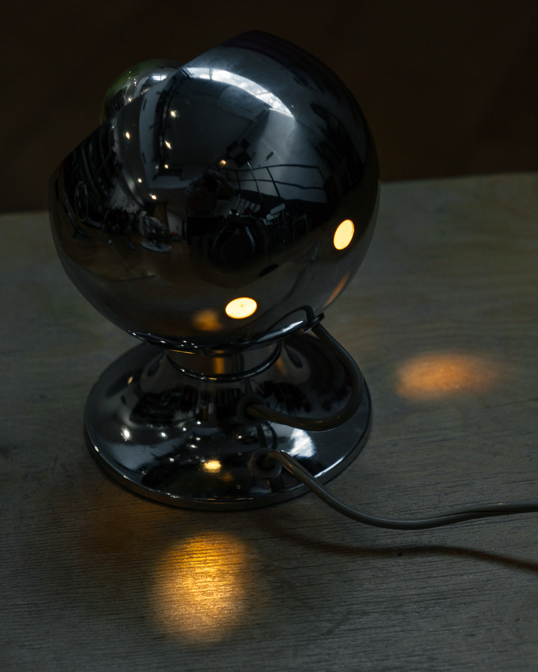 Vintage chrome eyeball table lamp from the 1970s with spherical shade and chrome-dipped bulb. Vecino Shop