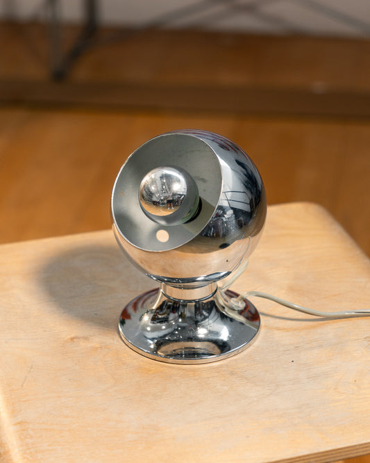 Vintage chrome eyeball table lamp from the 1970s with spherical shade and chrome-dipped bulb. Vecino Shop