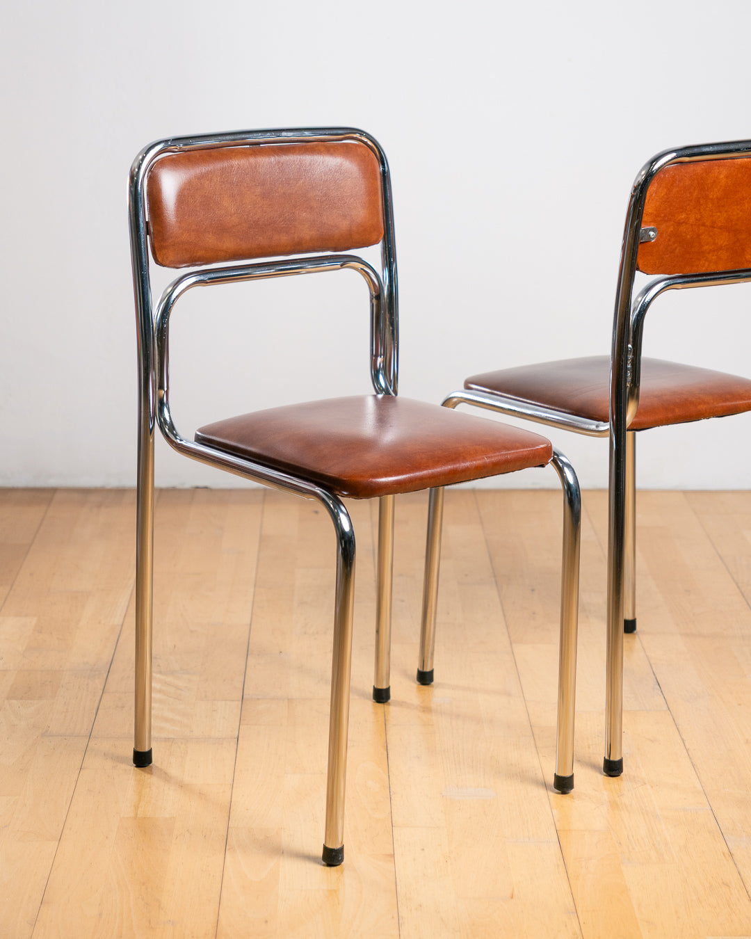 Set of two vintage 1970s Bauhaus tubular chrome dining chairs with brown PU leather upholstery. Stackable design. Vecino Shop