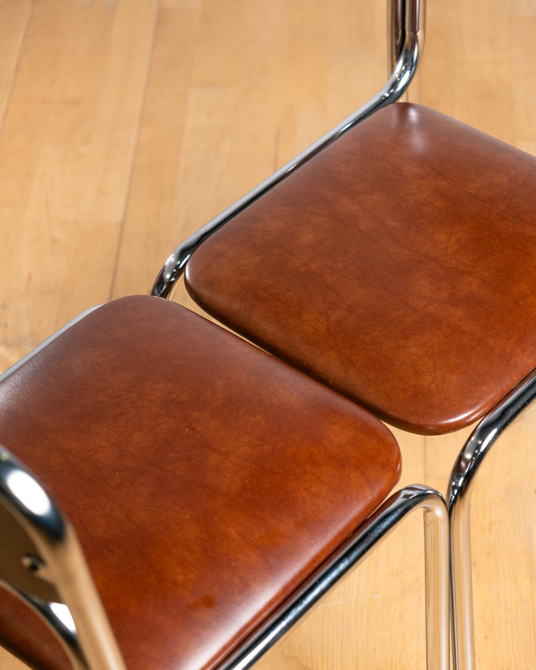 Set of two vintage 1970s Bauhaus tubular chrome dining chairs with brown PU leather upholstery. Stackable design. Vecino Shop