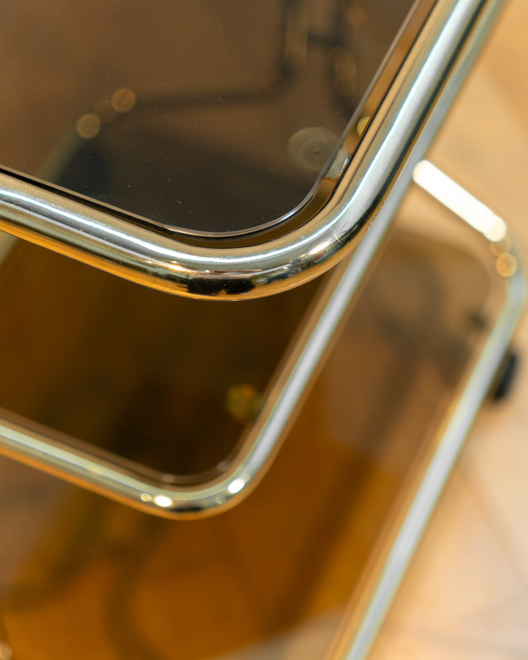 Rare 1970s tubular gold rolling side table with three smoked glass tiers and wheels, vintage Space Age design. Vecino Shop