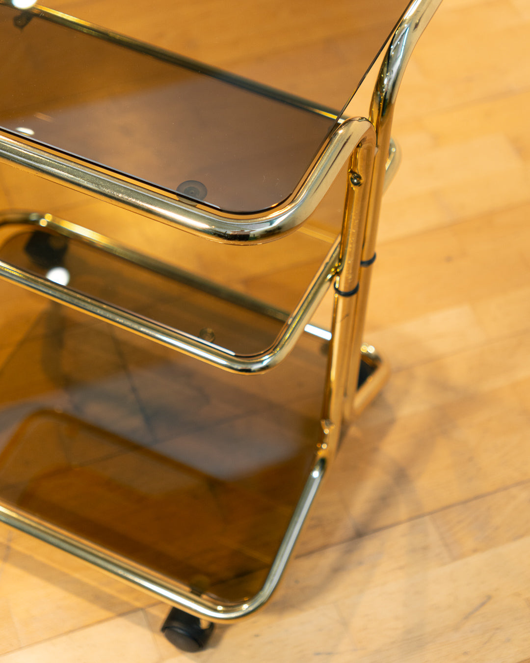 Rare 1970s tubular gold rolling side table with three smoked glass tiers and wheels, vintage Space Age design. Vecino Shop