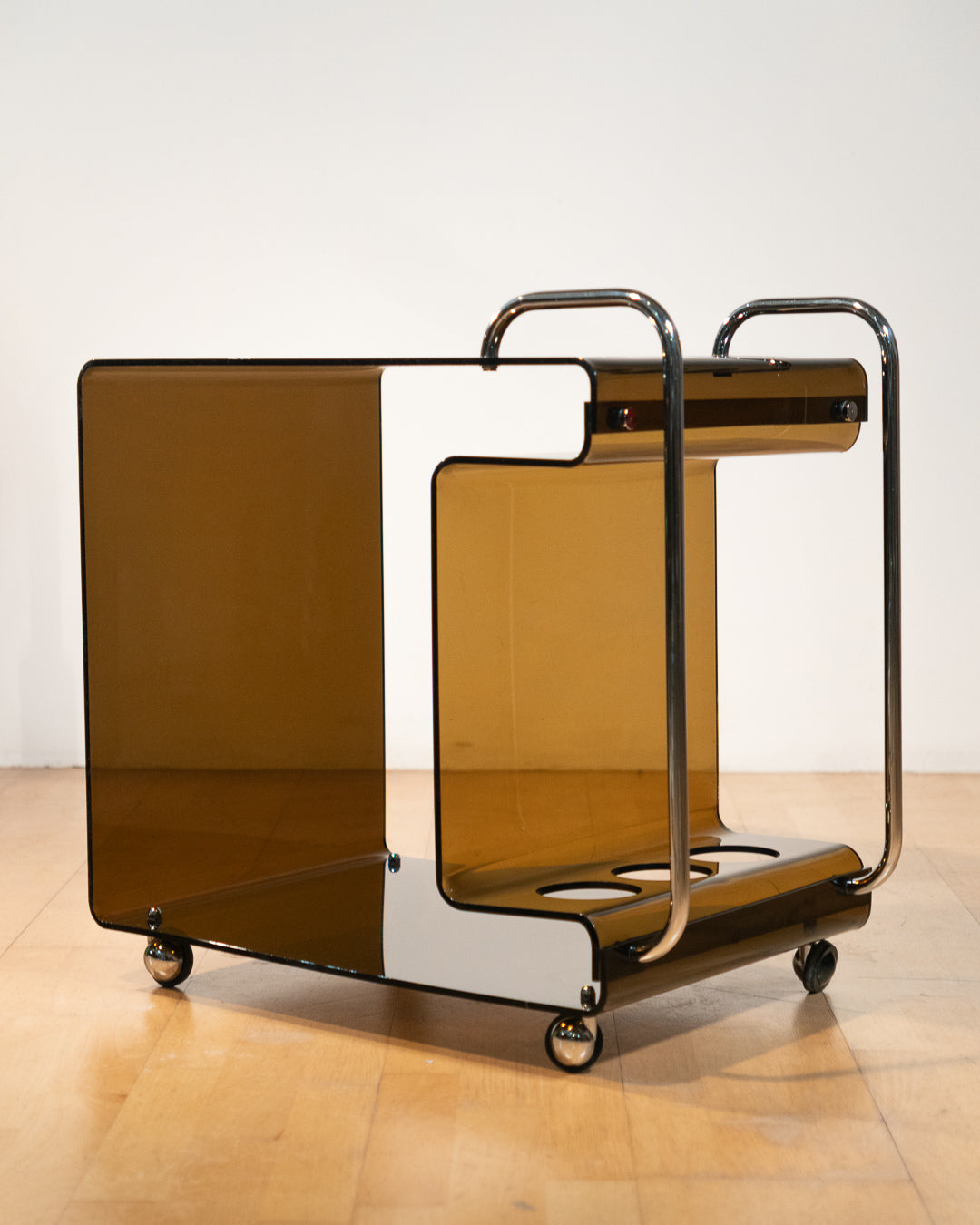 1970s smoked amber acrylic bar cart with chrome handles and casters, sculptural U-shaped design