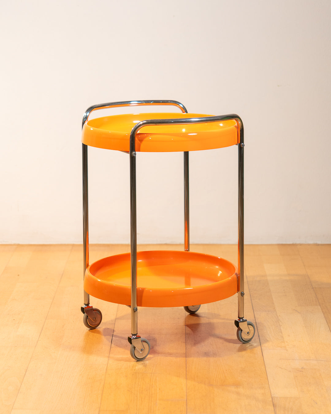 Rare 1970s round chrome bar cart with orange shelves, two tier design, restored vintage trolley with signs of use. Vecino Shop