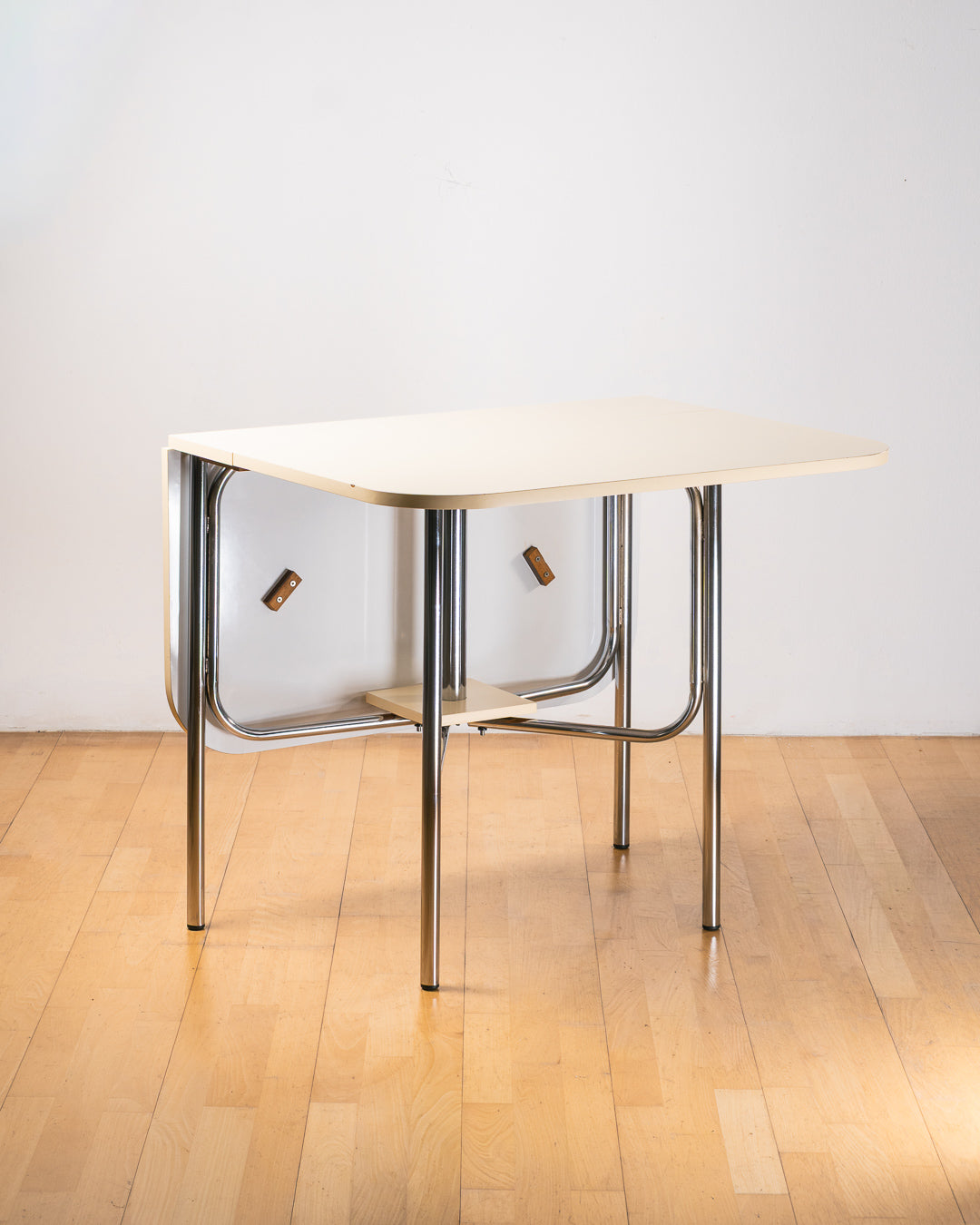 Vintage 1980s folding dining table with off white Formica table top, chrome tubular legs and rounded corners. Space Age space-saving design. Vecino Shop 