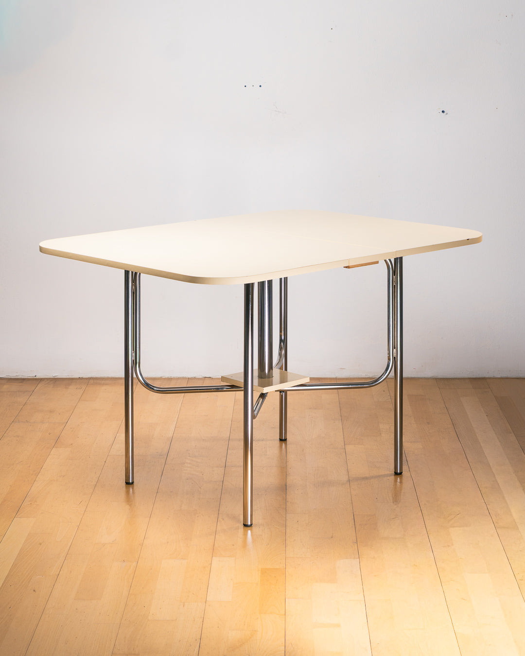 Vintage 1980s folding dining table with off white Formica table top, chrome tubular legs and rounded corners. Space Age space-saving design. Vecino Shop 