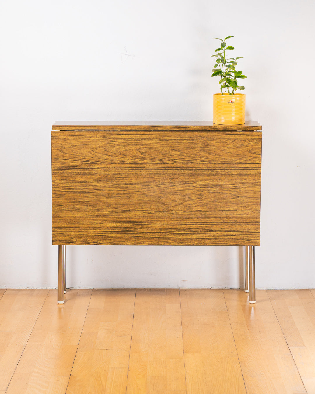 Vintage 1980s folding dining table with brown wood veneer Formica table top, chrome tubular legs and square corners. Space Age space-saving design. Vecino Shop 