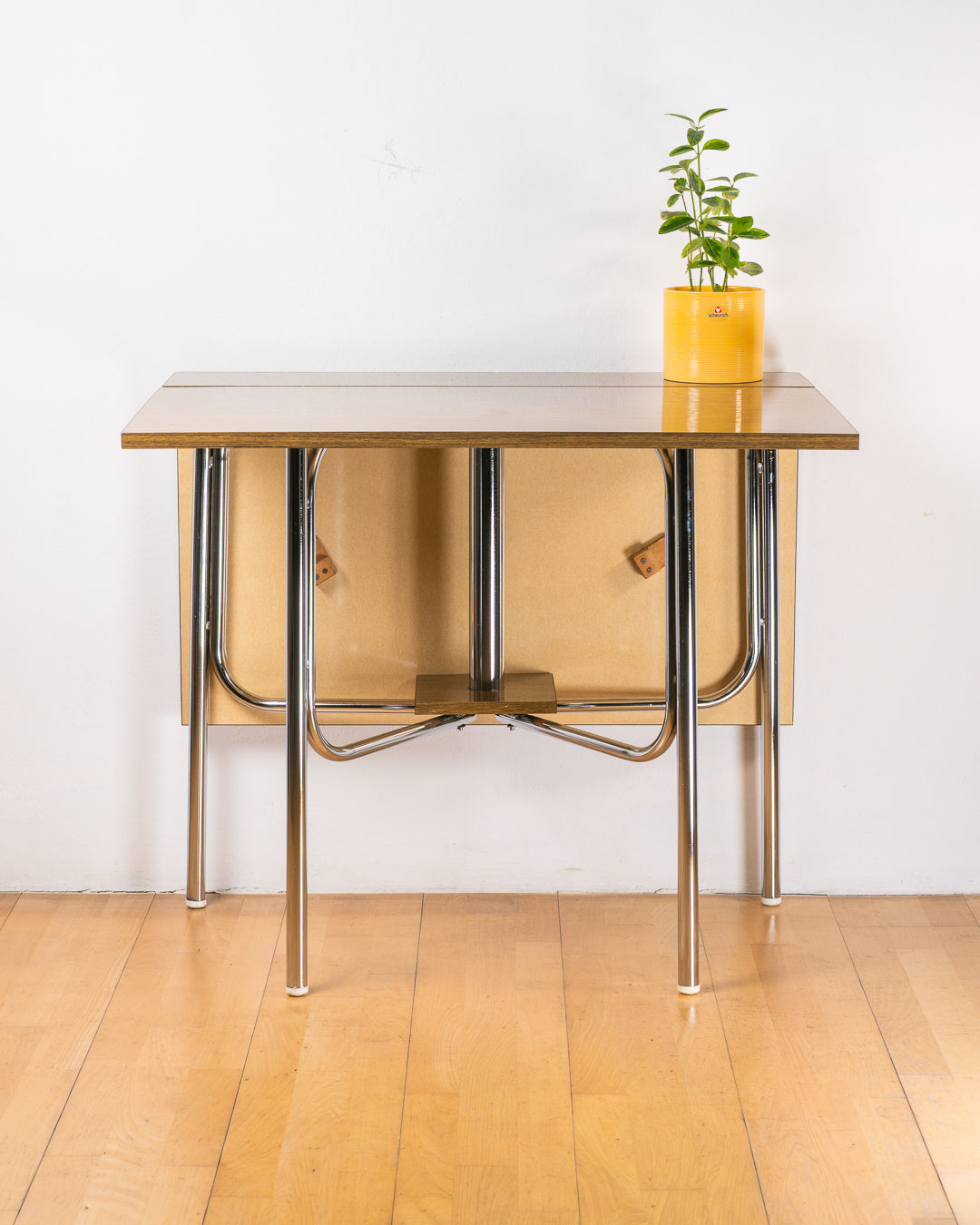 Vintage 1980s folding dining table with brown wood veneer Formica table top, chrome tubular legs and square corners. Space Age space-saving design. Vecino Shop 