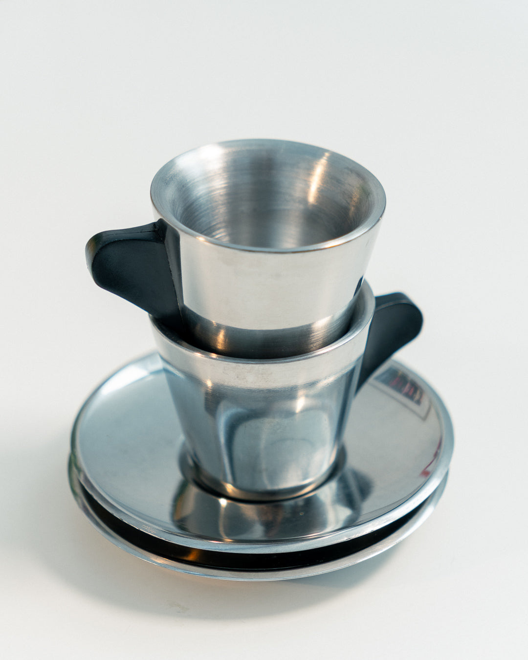 Vintage IKEA double-walled stainless steel espresso cup and saucer set from the 1990s with black plastic handles. Scandinavian minimalist design. Vecino Shop