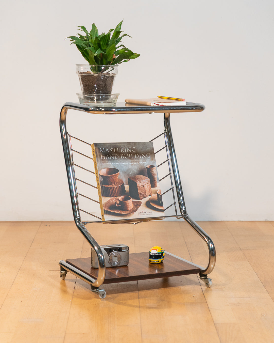 1970s chrome rolling side table with smoked glass top, wooden shelf, wheels, and magazine rack. Vecino Shop