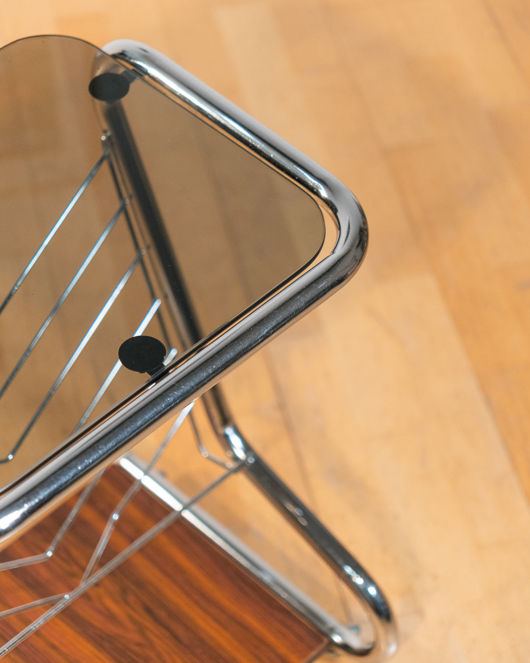 1970s chrome rolling side table with smoked glass top, wooden shelf, wheels, and magazine rack. Vecino Shop