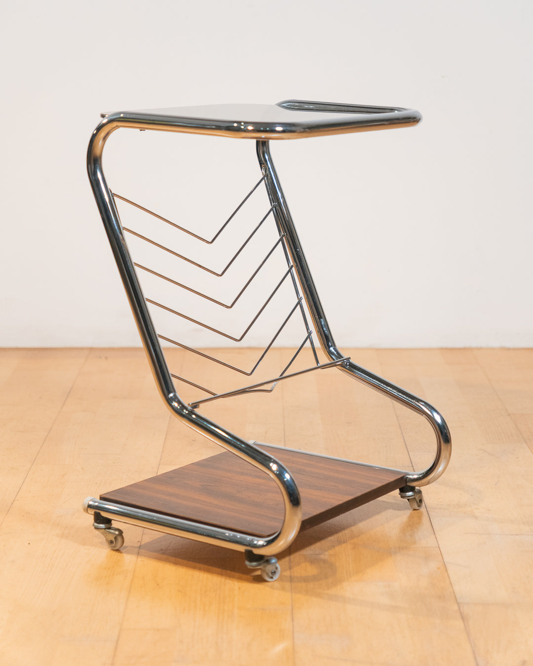 1970s chrome rolling side table with smoked glass top, wooden shelf, wheels, and magazine rack. Vecino Shop