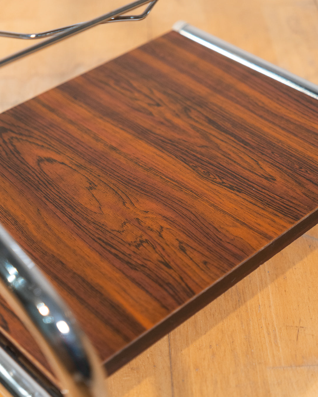 1970s chrome rolling side table with smoked glass top, wooden shelf, wheels, and magazine rack. Vecino Shop